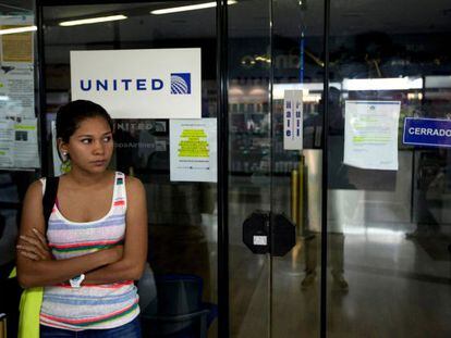Uma mulher espera diante de um escritório da United em Caracas.