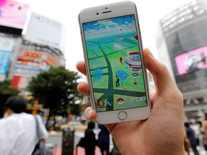 Usuário joga o Pokémon Go com o celular em uma movimentada rua de Tóquio.