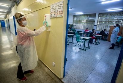 Mãe de aluno, contratada em um programa de temporários da Prefeitura, desinfeta um recipiente de álcool gel na escola de ensino fundamental Sylvia Martin Pires em São Paulo, em 8 de março de 2021.
