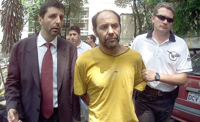 O líder dos sequestradores do publicitário Washington Olivetto, o chileno Maurício Hernandez Norambuena (c), é levado preso por policiais para ser apresentado na Delegacia Antissequestro (DEAS), em São Paulo, no dia 4 de fevereiro de 2002.