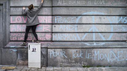 Uma jovem escreve, nesta quarta-feira, mensagem em muro da Praça da Bolsa de Bruxelas em homenagem às vítimas dos atentados terroristas.