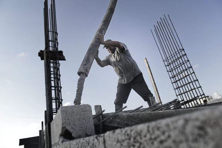 Um operário palestino derrama cimento no teto de um edifício.