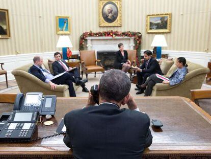 Barack Obama conversa por telefone com Raúl Castro no Salão Oval, na presença do Ben Rhodes e Ricardo Zúñiga, entre outros.