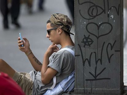 Jovem consulta celular em São Paulo.