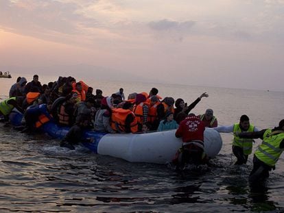 Um grupo de voluntários ajuda um bote motorizado a chegar à ilha grega de Lesbos.