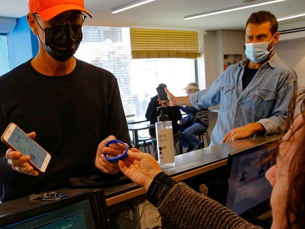A man shows his "green pass" (proof of being fully vaccinated against the coronavirus) at the reception desk of a gym, in the Israeli coastal city of Tel Aviv, on February 21, 2021. - Israel took a step towards normalcy today, re-opening a raft of businesses and services from pandemic lockdowns, but with some only available to fully vaccinated "green pass" holders.  
Nearly three million people, almost a third of Israel's population, have received the two recommended doses of the Pfizer/BioNTech coronavirus vaccine, the world's quickest inoculation pace per capita. (Photo by GIL COHEN-MAGEN / AFP)