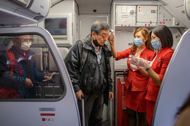 Duas aeromoças medem a temperatura de passageiros num embarque no aeroporto de Incheon (Coreia do Sul).