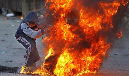 Palestino queima um pneu em protesto em Jerusalém.