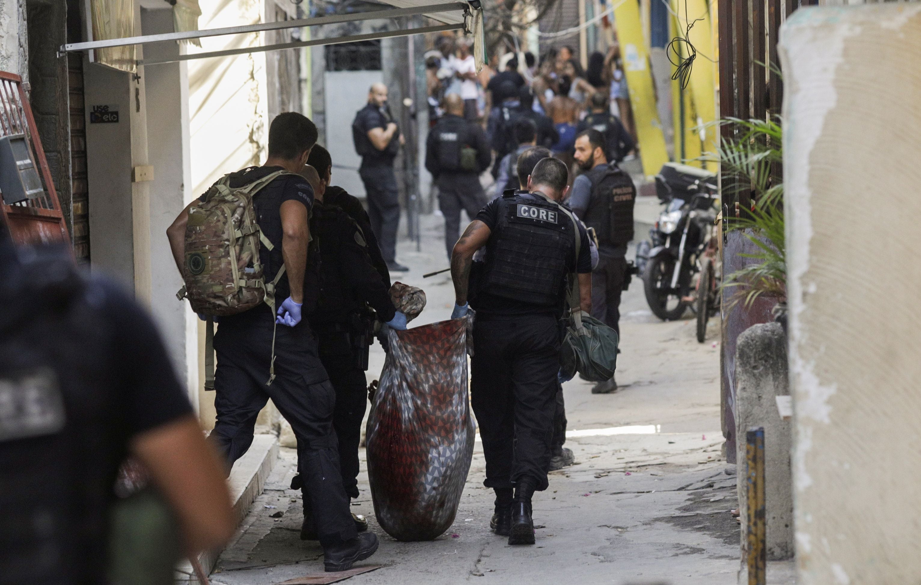 Policiais carregam corpos de pessoas mortas durante a operação do Jacarezinho, em 6 de maio. 