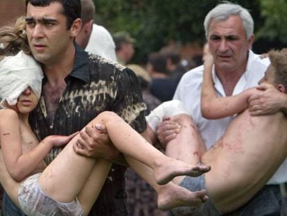 Dois homens carregam crianças resgatadas após a ação das forças russas em Beslan, em 2004 (arquivo).
