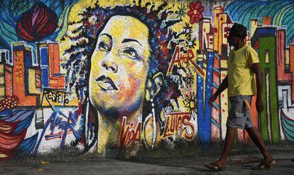 Homem caminha em frente a um mural de Marielle Franco, no Rio de Janeiro.