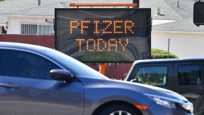 Automóveis passam diante uma placa informativa anunciando a vacina da Pfizer em um centro de imunização de Los Angeles (Califórnia).