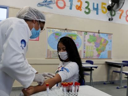 Enfermeira tira amostra de sangue de estudante em São Paulo para teste de coronavírus.