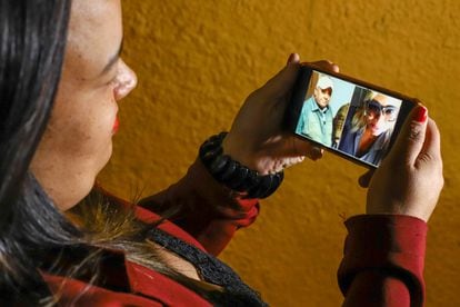 A recepcionista Maíra Diniz Câmpara segura celular com fotos do pai e da irmã, vítimas da covid-19