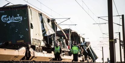 Vários operários passam junto ao trem de carga na ponte do Grande Belt, em Nyborg (Dinamarca).