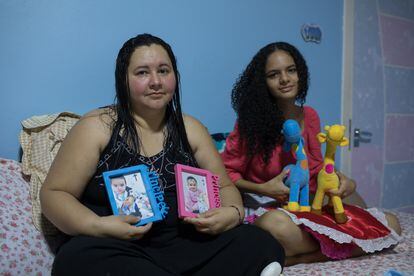 Mayra Pires Lima, de 38 anos, ao lado da sobrinha Evelyn, de 15 anos. Elas seguram as fotos, roupas e brinquedos do casal de bebês Gabriel e Sophia. As crianças ficaram órfãs após a morte da mãe por covid-19. Mayra ficou com a guarda de todos os sobrinhos.