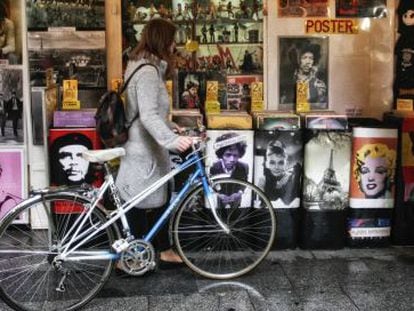 Jovem olha discos de vinil junto a sua velha bicicleta.