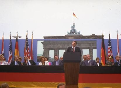 O muro de Berlim dividiu essa cidade alemã em duas metades entre 1961 e 1989. A frase acima, dita pelo então presidente dos Estados Unidos num discurso próximo ao Portão de Brandemburgo, ao lado do Muro, em 12 de junho de 1987 (sem que o líder soviético estivesse presente), não teve o poder de derrubá-lo, mas amplificou a ideia de que aquela sombria construção era não só uma vergonha para a Alemanha como também um atentado “à liberdade do ser humano”, como disse Reagan. Finalmente, foi a insurgência contra a opressão soviética iniciado na Hungria e na Polônia, seguida pela fuga em ondas de refugiados da Alemanha Oriental, que levou um novo Governo na RDA a abrir as portas e, em novembro de 1989, demolir o muro. Na imagem, Ronald Reagan de pé no palanque com o chanceler da Alemanha Ocidental, Helmut Kohl (à dir.) e o embaixador norte-americano Richard Burt (à esq.), em frente ao Portão de Brandemburgo, em 1987.