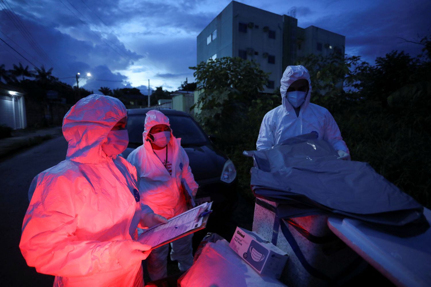 Agentes de saúde municipais se preparam para examinar o corpo de uma pessoa em meio ao surto de coronavírus em Manaus.
