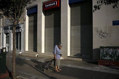 Uma mulher passa adiante de uma sucursal bancária fechada, na segunda-feira em Atenas.