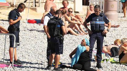 Uma mulher tira a camisa, enquanto a polícia aplica uma multa em Nice.