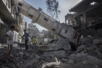 Vários palestinos passam sob o mirante de uma mesquita, que desmoronou e destruiu a fachada de uma casa na cidade de Gaza, em 30 de julho de 2014. A mesquita foi um dos alvos dos bombardeios do Exército israelense na noite passada.