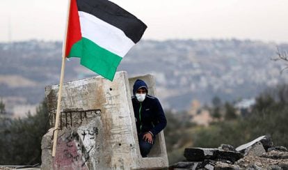 Manifestante palestino se refugia em um bloco de concreto.