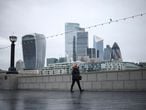 A person wearing a protective mask walks at the South Bank of the River Thames, with the financial district in the background, amid the coronavirus disease (COVID-19) outbreak, in London, Britain, January 5, 2021. REUTERS/Henry Nicholls