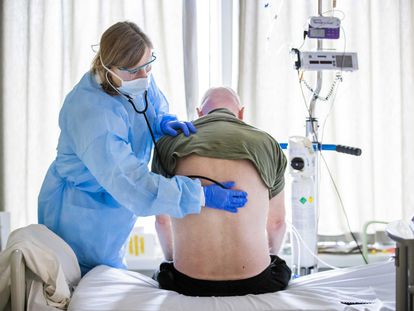 Uma médica ouve os pulmões de um paciente que está se recuperando da admissão na UTI por Covid-19.