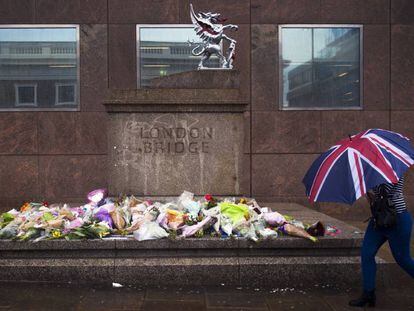 Mulher passa em frente aos ramos de flores deixados em homenagem às vítimas do atentado do sábado na London Bridge.