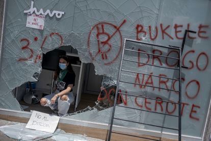 Uma manifestante dentro de um caixa de bitcoins destruído durante os protestos de quarta-feira.