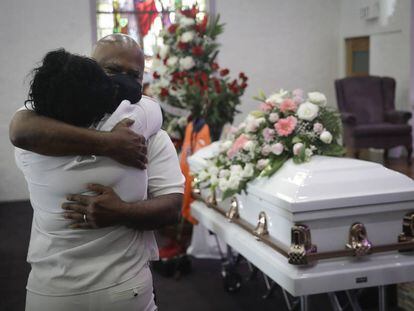 Dos personas se abrazan en un funeral de una mujer fallecida por covid en Los Ángeles.