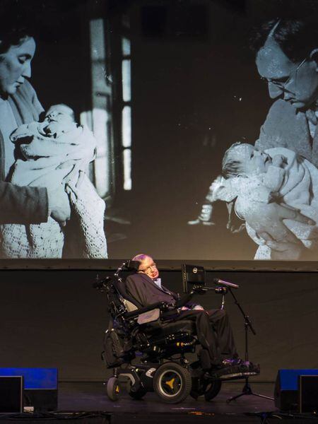 Stephen Hawking, diante de duas fotos com sua mãe e seu pai.