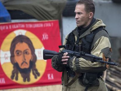 Um rebelde ucraniano diante de uma bandeira do Batalhão Ortodoxo Russo.