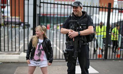 Menina posa com um policial antes do show de Ariana Grande em Manchester, neste domingo.