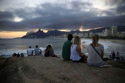 Turistas observam o p&ocirc;r do sol no Arpoador, no Rio.