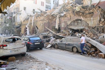 Uma mulher caminha nesta quarta-feira junto a edifícios e veículos danificados pela explosão da véspera em Beirute.