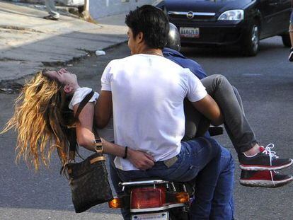 Genesis Carmona &eacute; levada em uma moto depois de ser atingida por um tiro.