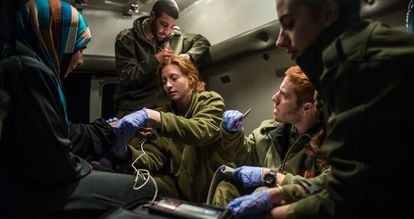 Militares paramédicos israelenses atendem um grupo de sírios nas Colinas de Golã.