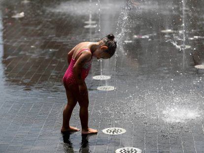 Menina se refresca em chafariz de Madri, durante uma onda de calor.