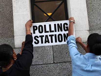 Trabalhadores colocam cartazes em um colégio eleitoral de Londres.
