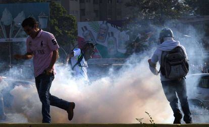 Vários manifestantes tentam se proteger das bombas lacrimogêneas nesta terça em Caracas.