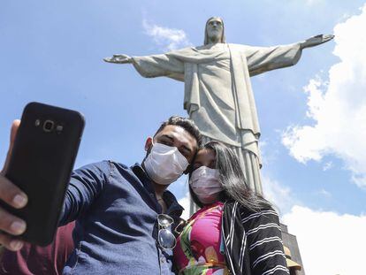 Turistas no último dia 13 tiram foto no Cristo Redentor, usando máscaras.