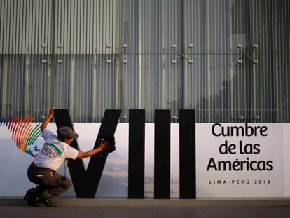 Mulher limpa o logotipo da Cúpula das Américas em Lima