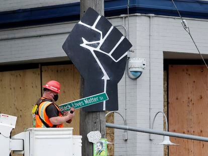 Funcionário retira placa "Black Lives Matter St." em Seattle, EUA.