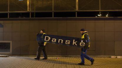 Dois operários retiram o cartaz do Danske Bank na filial de Tallin (Estônia), em 5 de outubro de 2019.