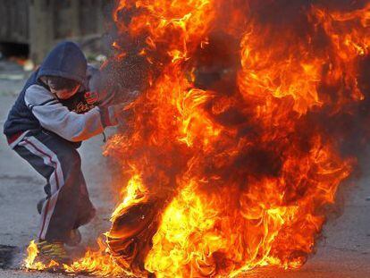 Palestino queima um pneu em protesto em Jerusalém.