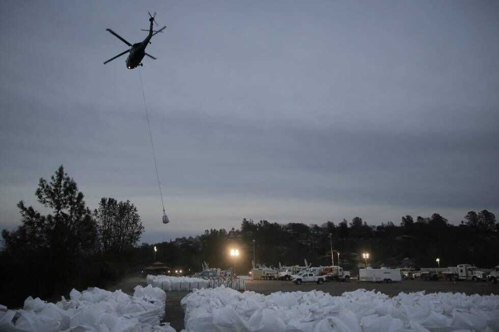 Helicóptero transporta um saco com pedras para depositá-lo na área que sofreu erosão.