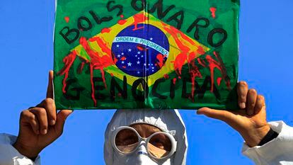 Manifestante levanta bandeira do Brasil com a inscrição "Bolsonaro genocida" em protesto em Brasília, na quarta.