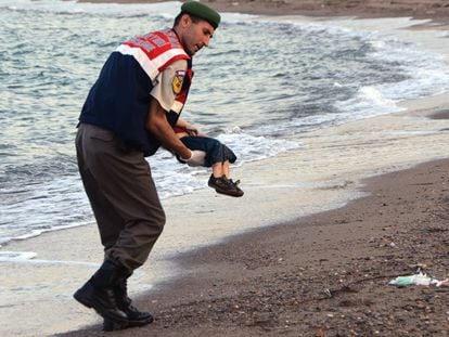 Um policial recolhe o cadaver de uma criança em uma praia de Turquia.